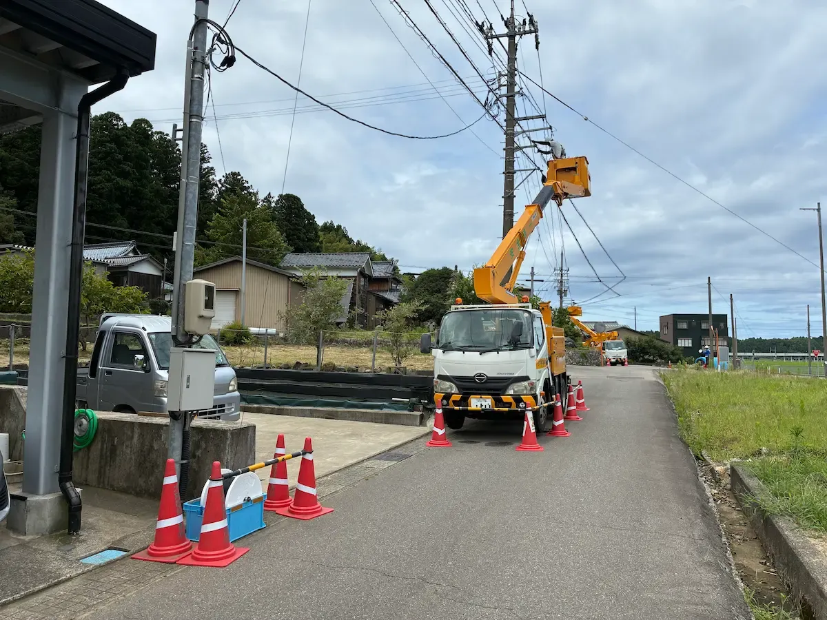高所作業車を使って電柱上の設備工事にあたる大栄電設工業のスタッフ